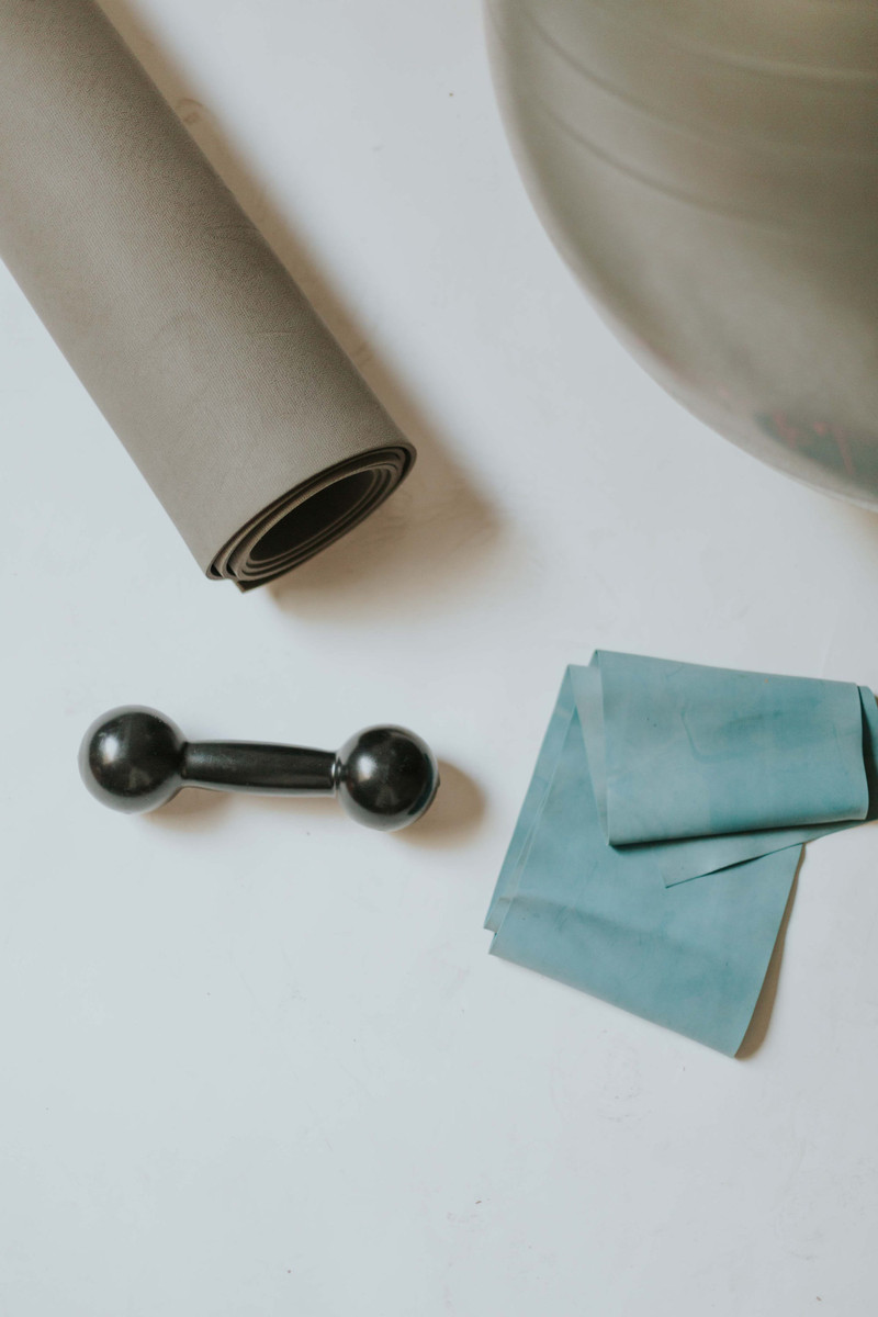 A rolled mat, a small dumbbell and a band on white.