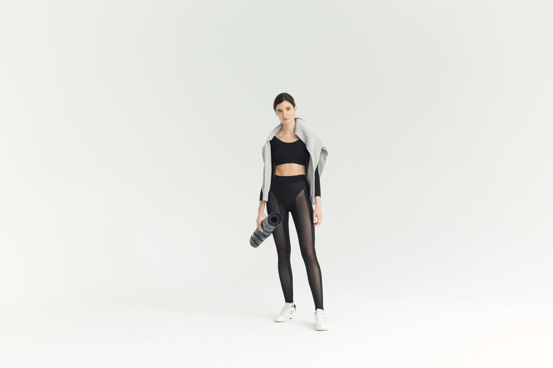 Mesh-panel leggings and a crop top, a mat under the arm.