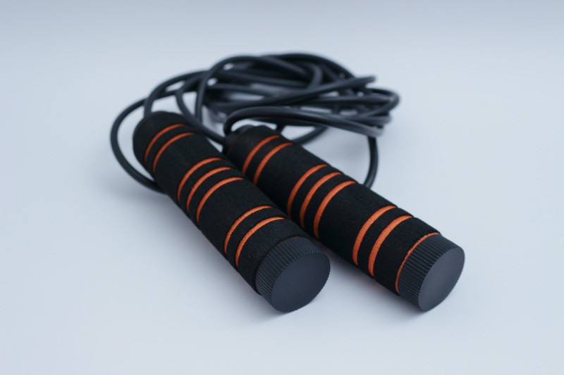 A black and orange speed rope on white.