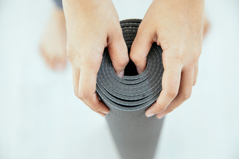 A grey yoga mat being rolled.