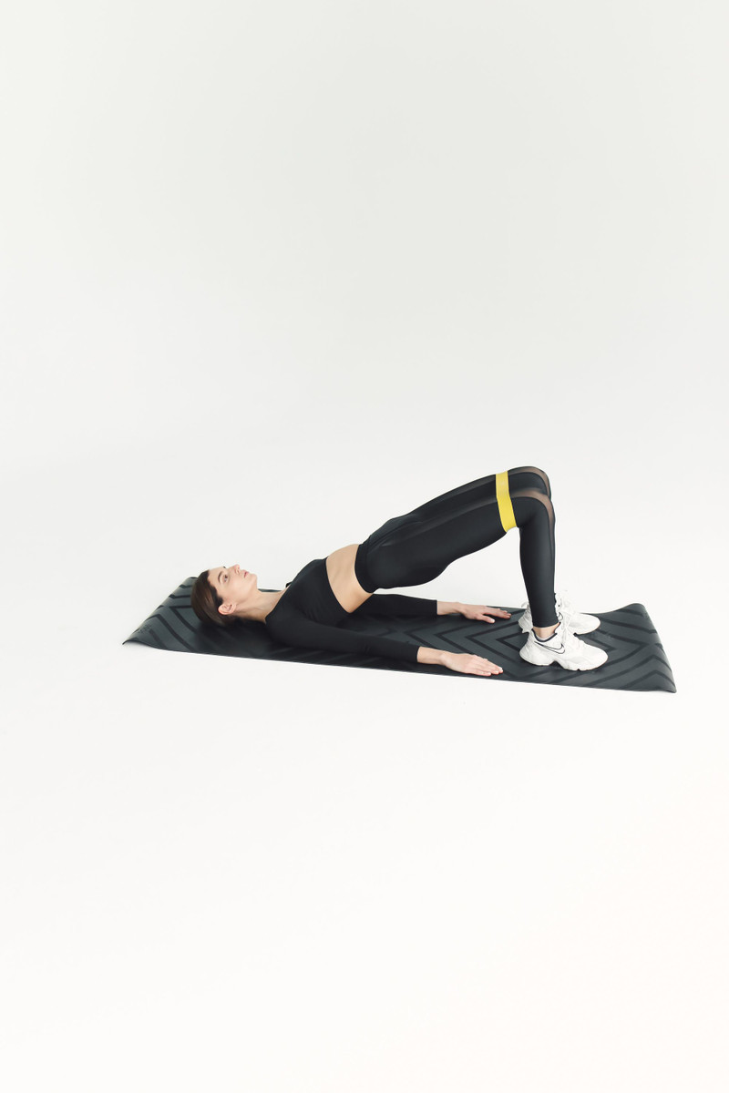 A glute bridge on a mat with a mini loop band.