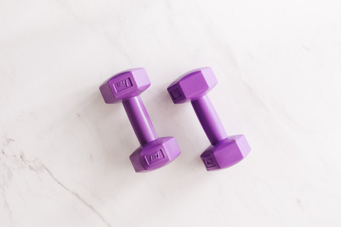 Purple cast dumbbells on white marble.