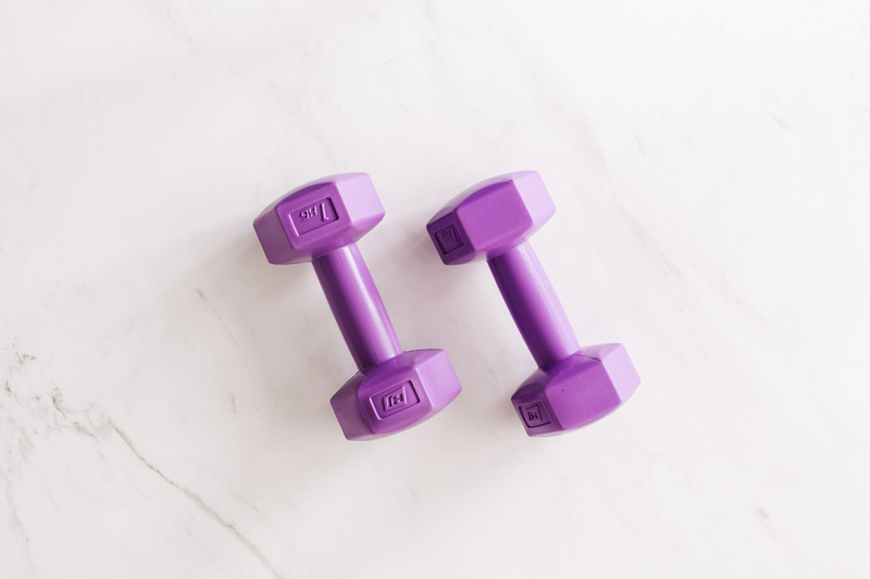 Purple cast dumbbells on white marble.