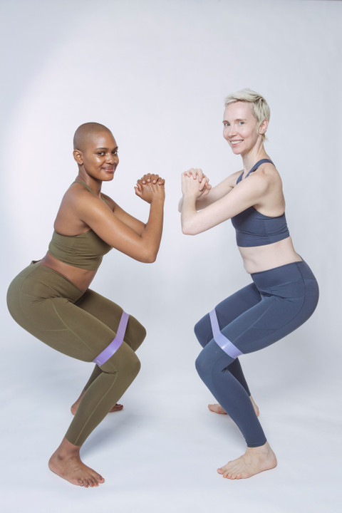Two women squatting in the sculpt sets with fabric bands.