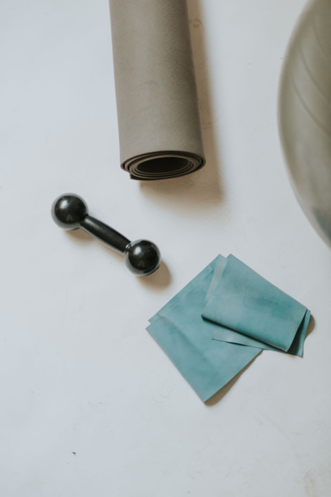 A mat, a 1 kg dumbbell and a teal band, from above.
