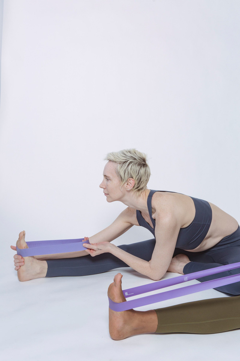 A seated stretch with a fabric band around the feet.