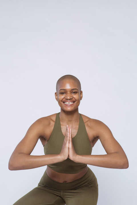 An olive sports bra and leggings, hands together.
